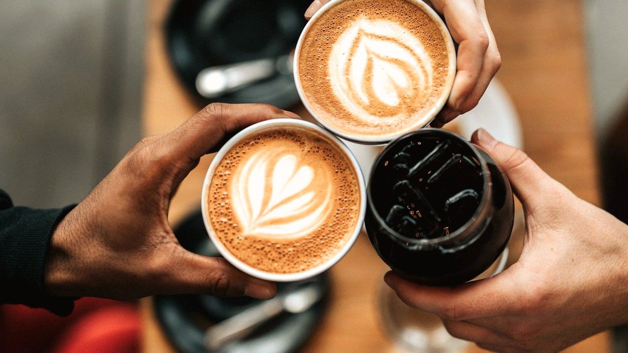 Regular cafe customers toasting latte-art coffees at a table