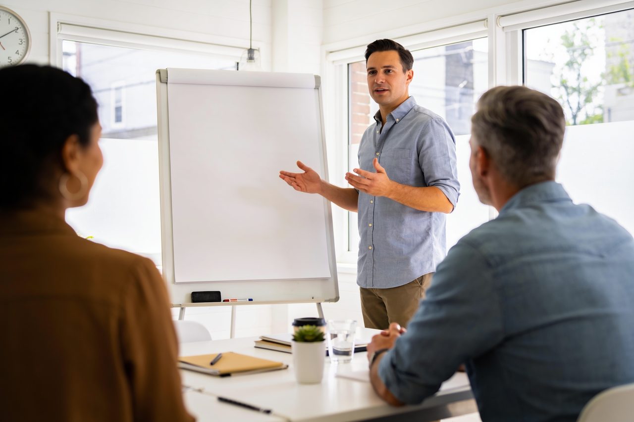 Business owner leading a sales strategy session at a whiteboard