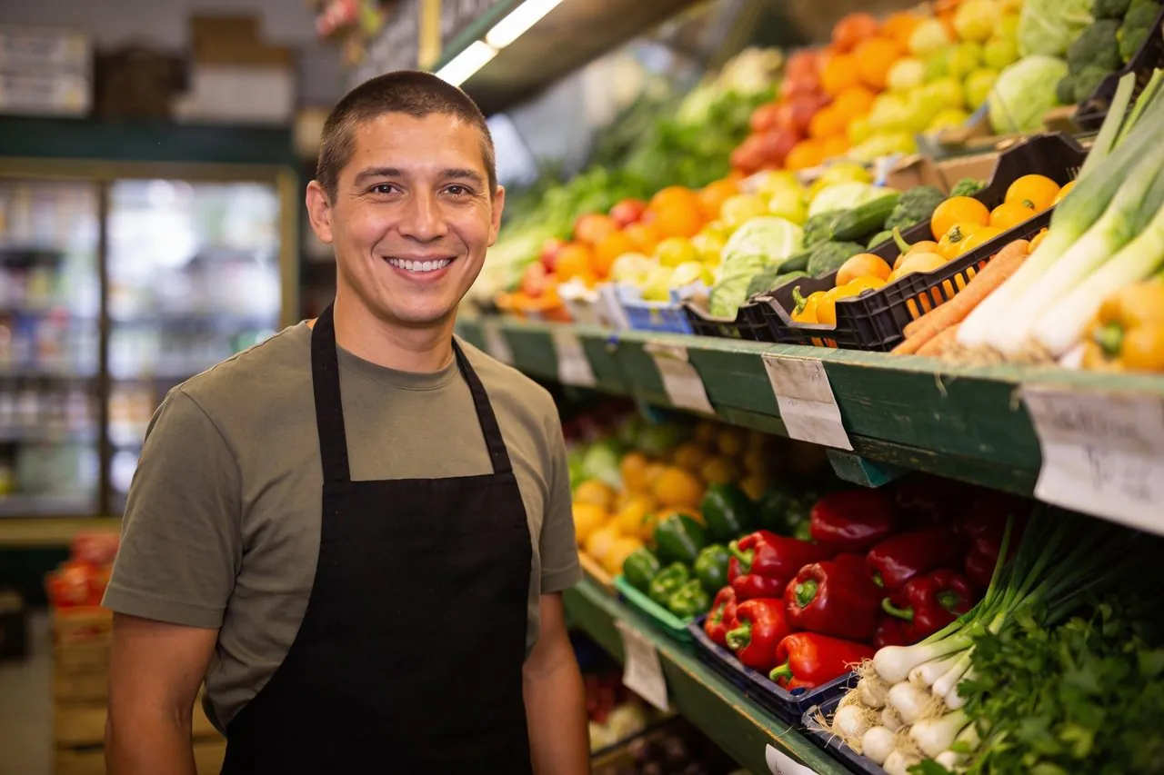 Grocery market owner standing among fresh produce in his store