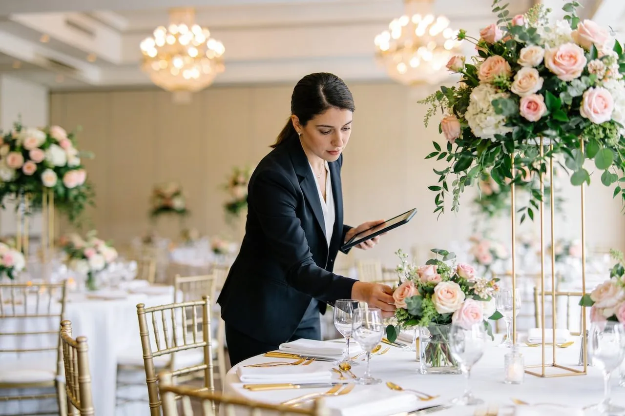 Wedding planner arranging floral centerpieces at a reception venue