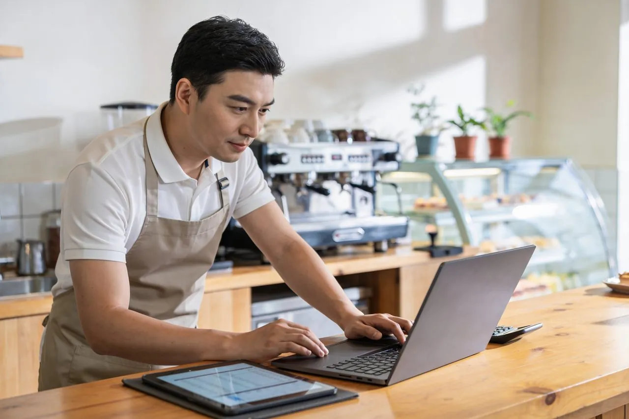 Cafe owner reviewing business finances on a laptop at the counter