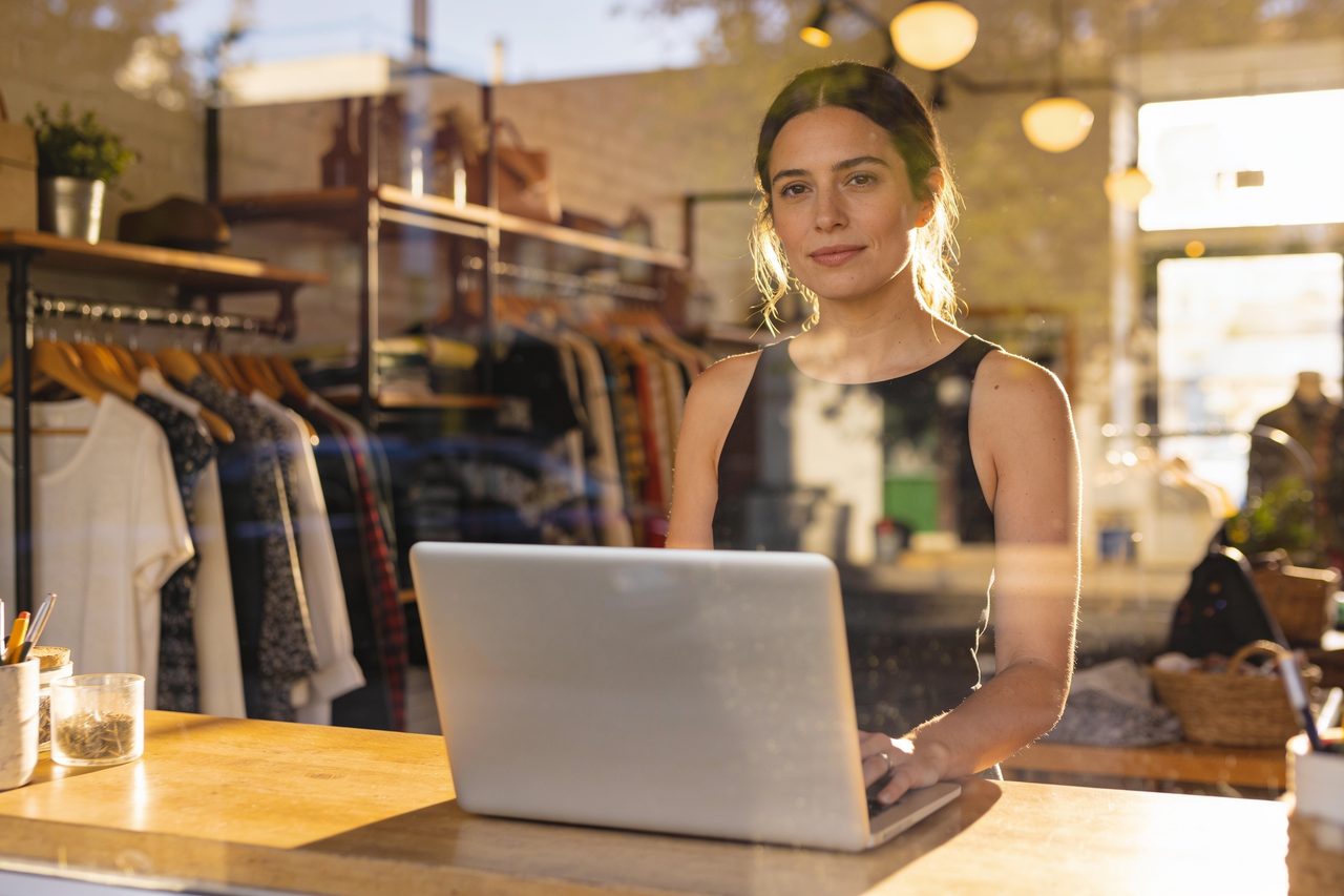 Boutique owner at her shop counter working on a laptop after getting her business license