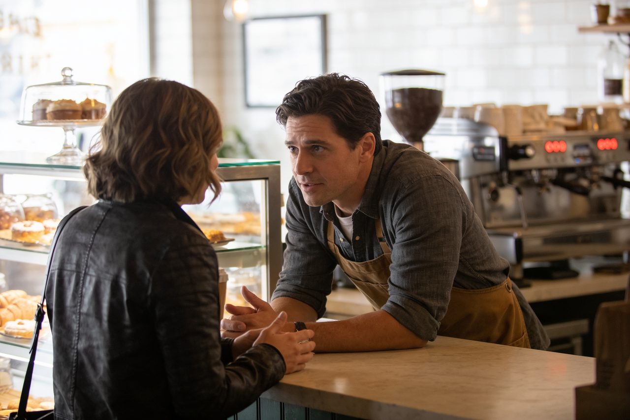 Coffee shop owner leaning across the counter listening to a customer complaint
