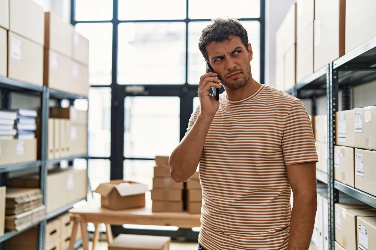 Warehouse owner on the phone looking skeptical about a suspicious funding offer