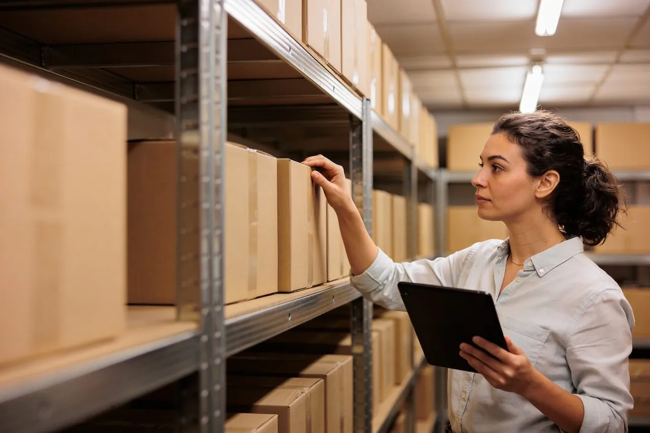 Shop owner checking stock levels on a tablet in her stockroom