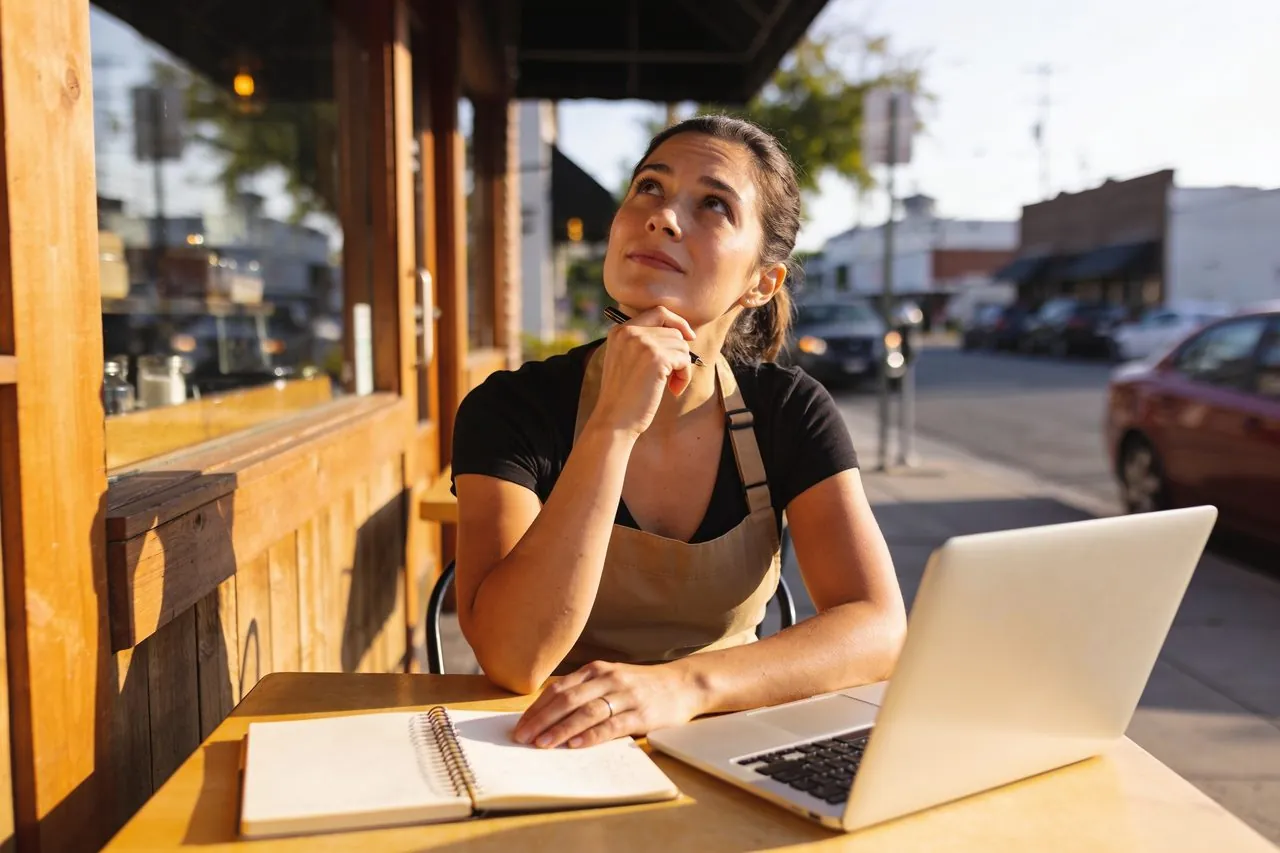 Cafe owner planning her business goals outside her shop