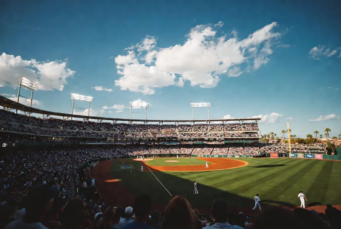 MLB Spring Training game in Arizona — packed stadium with palm trees in the distance, where The Broker Shop is a 2026 sponsor